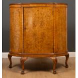 A 1930's burr elm bow fronted cabinet, with a single paneled door, four cabriole legs and hairy