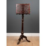 A late 19th century adjustable music stand with fret carved decoration and a tripod base, 41cm wide,