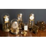 A group of seven various anniversary clocks, four under glass domes together with a brass carriage