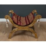 An Egyptian style gilt wood carved stool, with burgundy and gold upholstered seat, 74cm wide, 49cm
