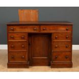 A late Victorian mahogany knee hole desk with eight drawers and a central cupboard with a panelled