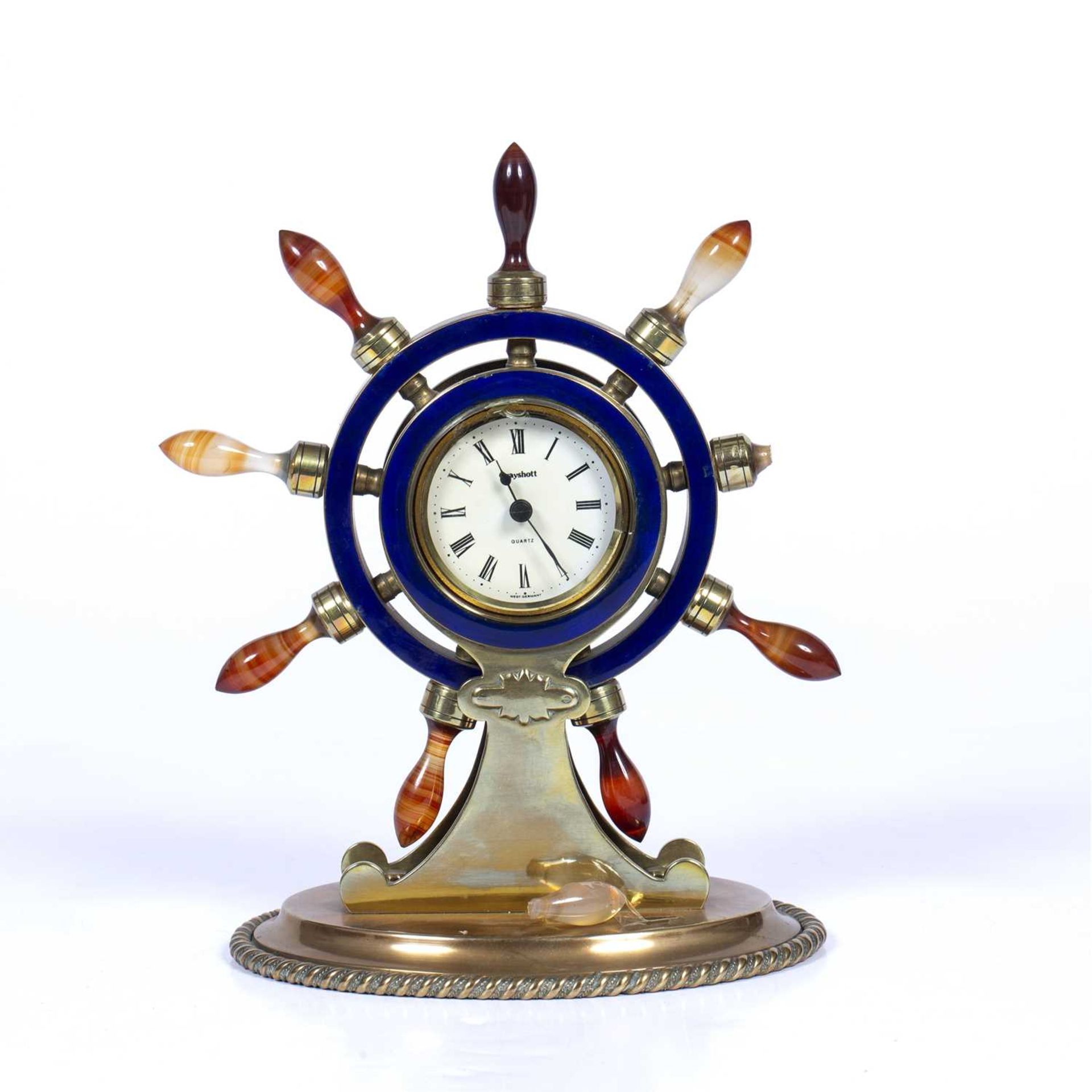 Brass and onyx ship's wheel model clock inset with blue enamel and on an oval base, with a later