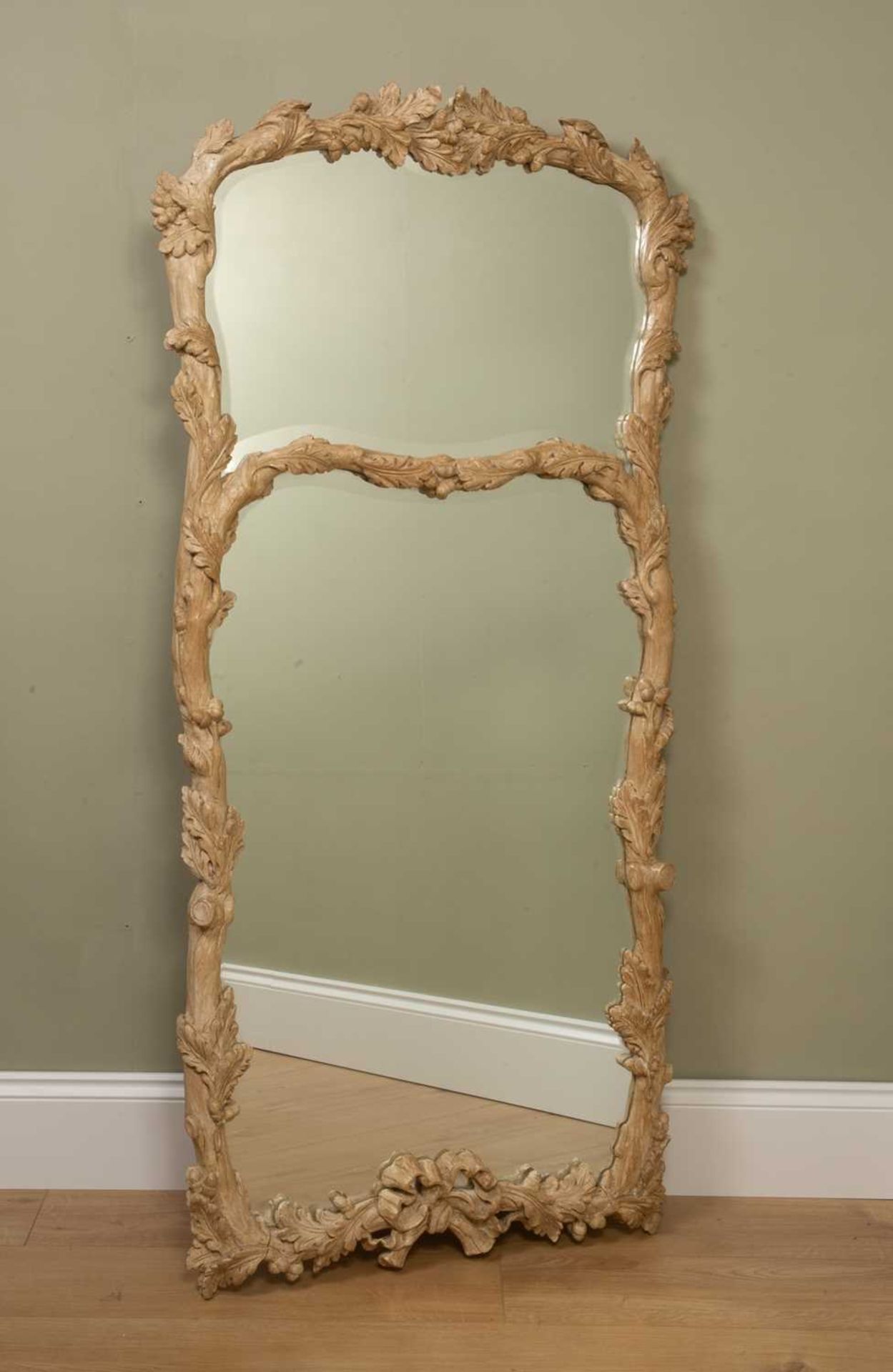 An 18th century-style limed carved wood wall mirror or pier glass, the twin shaped bevelled mirror