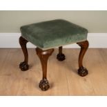 A Georgian walnut footstool with green upholstered top, on cabriole legs, and ball and claw feet,