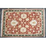 An Agra rug with red ground decorated with pale foliate motifs within a green and red banded border,