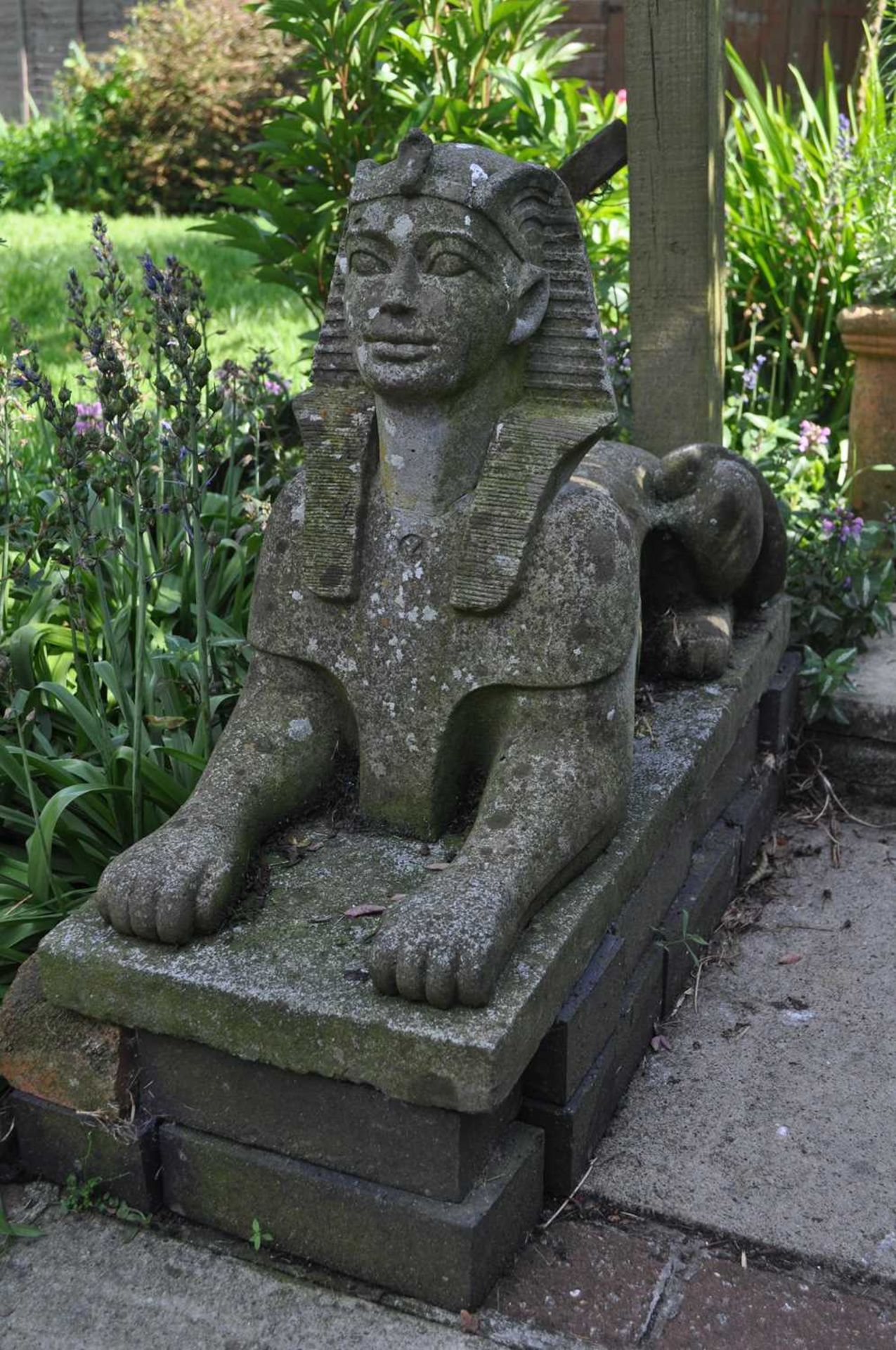 A garden sculpture in the form of a sphinx, 76.5cm long, 31cm wide, 49cm highWeathered overall.