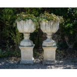 A pair of cast reconstituted stone garden urns decorated with acanthus leaves on octagonal bases and