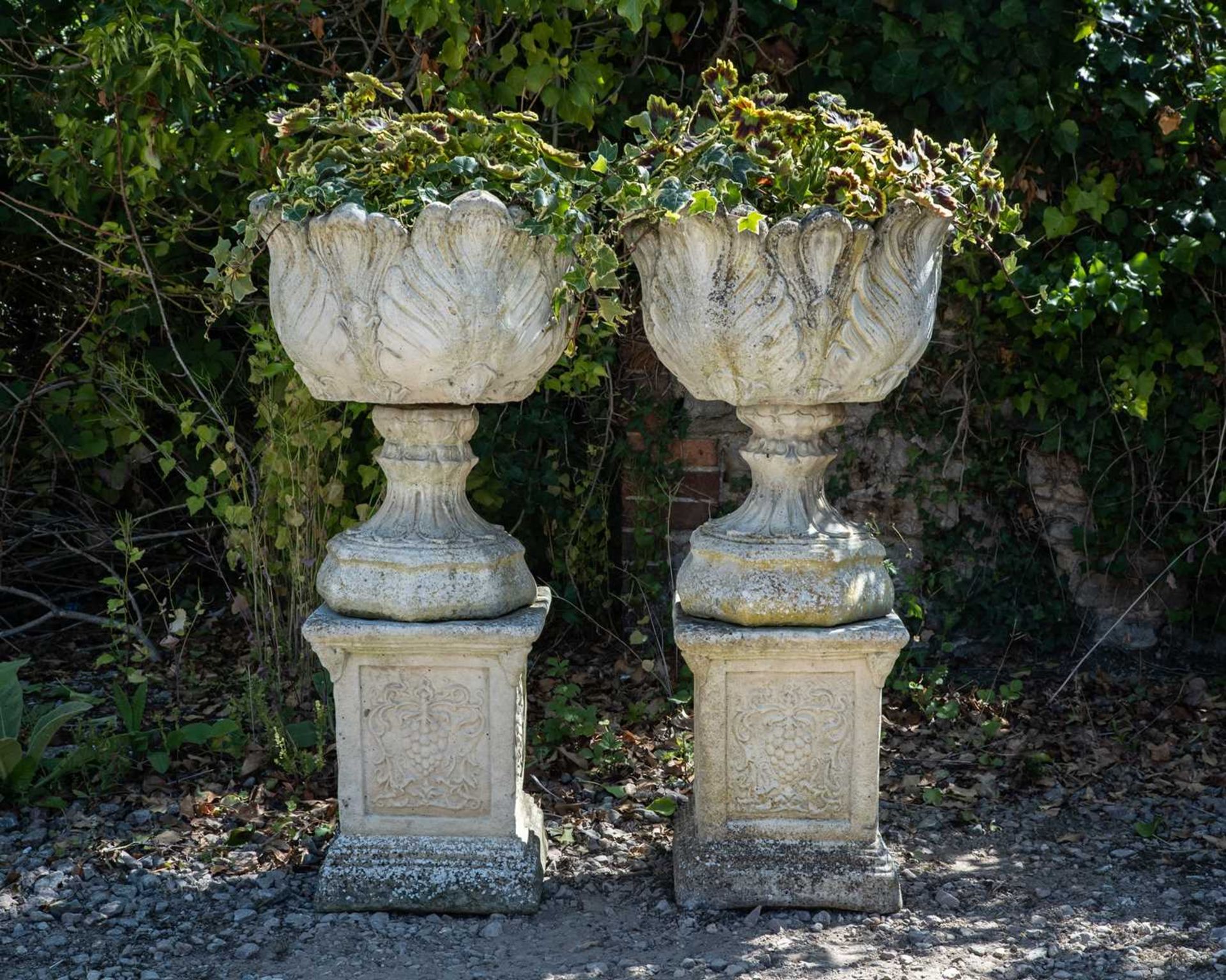 A pair of cast reconstituted stone garden urns decorated with acanthus leaves on octagonal bases and