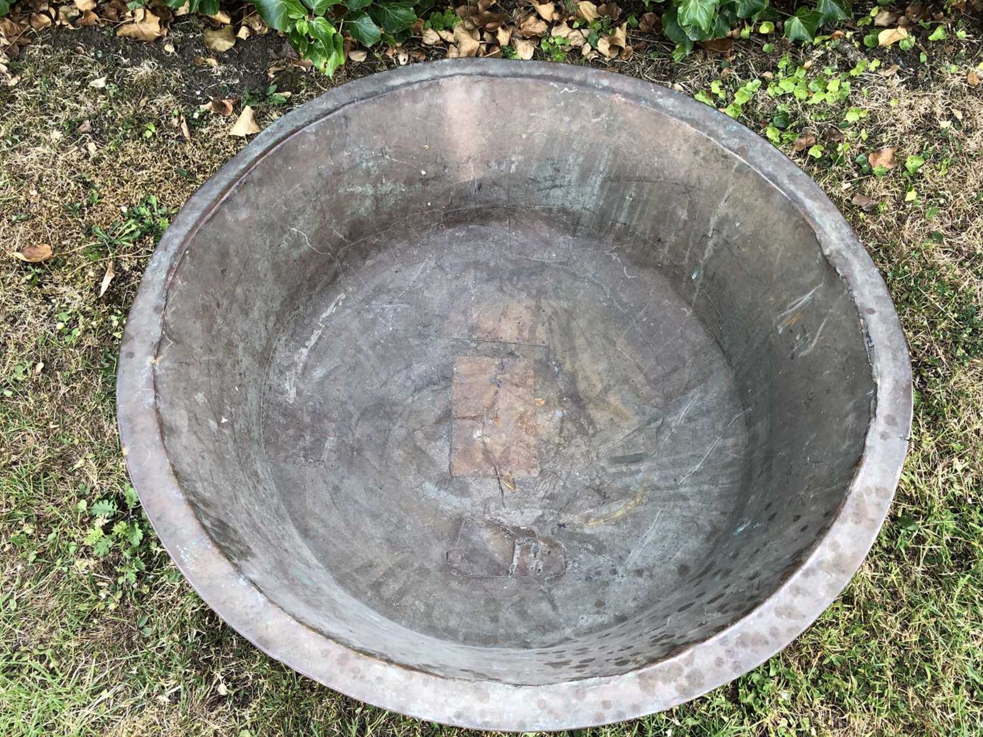 A large continental shallow copper bowl, with rivetted patches, 76cm diameter, 25.5cm highWith - Image 2 of 4