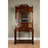 A Victorian hall stand with central mirror flanked by brass coat hooks above carved and tile