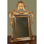 A giltwood dressing table mirror, the cushion shaped frame with mirrored slips within scrolling
