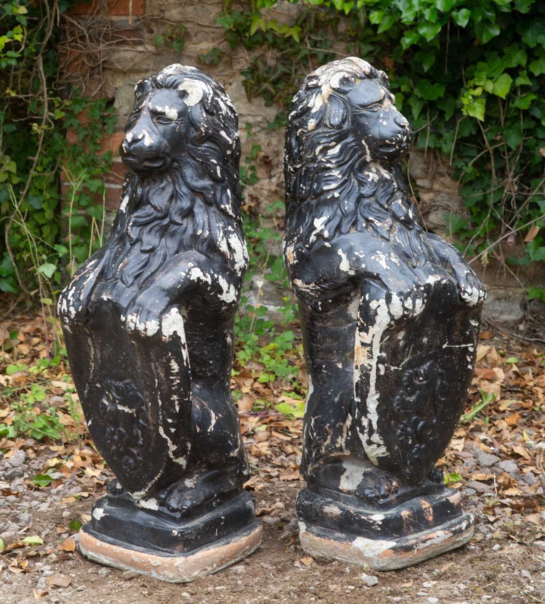 A pair of black painted cast reconstituted stone heraldic lions seated holding shields, each - Image 2 of 3