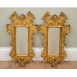 A pair of modern decorative gilt composite moulded wall mirrors with mask ornament to the break arch
