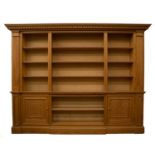 A neoclassical-style large pine library bookcase, the dentil cornice above three sections for