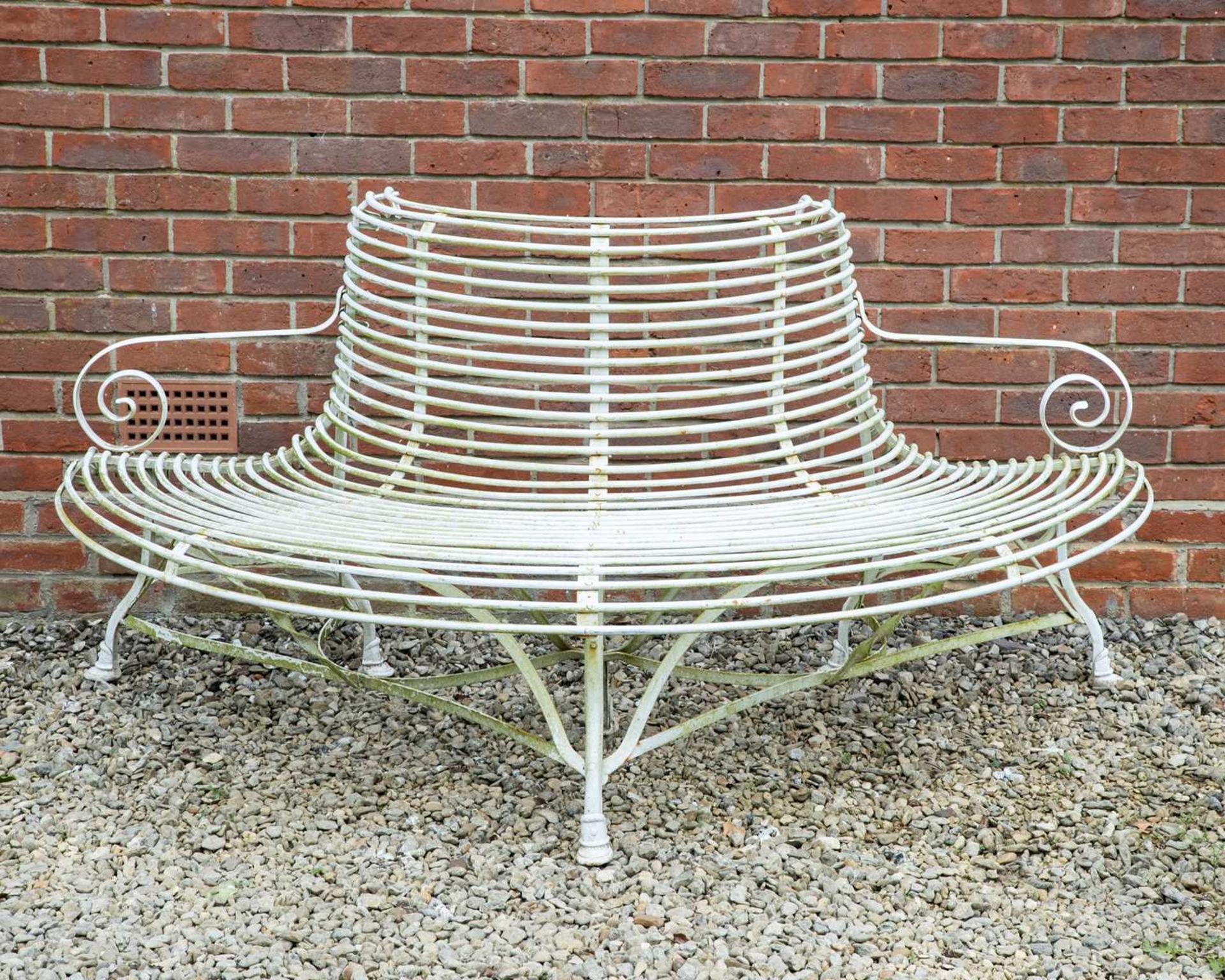 A white painted wrought iron semi-circular tree bench with scrolling arms, approximately 183cm