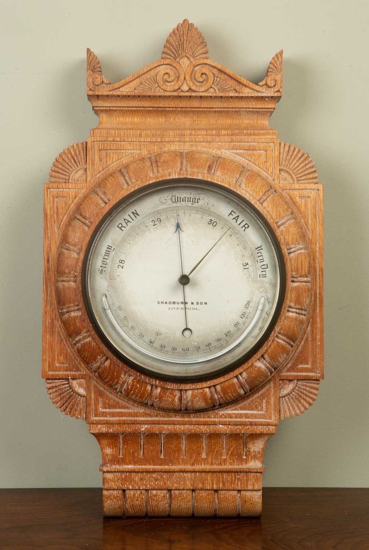 A Victorian aneroid barometer with Greek Revival limed oak case, around a silver dial with