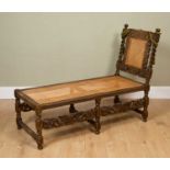 A Carolean-style oak day bed with caned drop end and seat, barley twist ornamented supports and