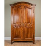 A French walnut armoire with arching panelled doors enclosing shelves within and all standing on