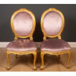 A pair of gilt framed oval back side chairs, with velvet upholstery on cabriole supports, 42cm wide,