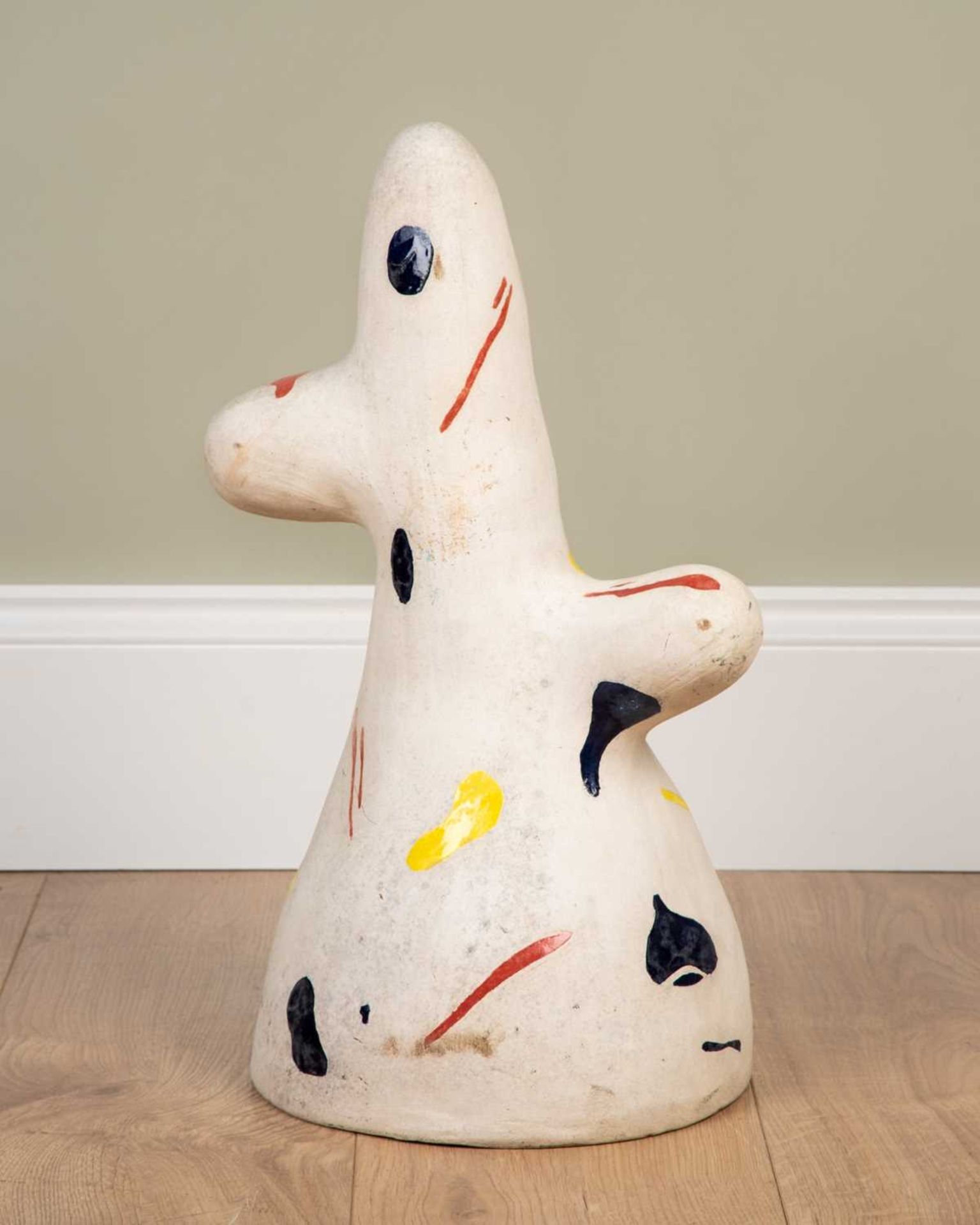 An abstract ceramic sculpture, with splashes of coloured glaze in blues, yellows and red,