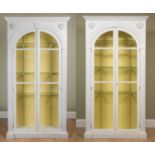 A pair of white painted country house display cabinets of modern manufacture with arching glazed