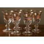 A set of six gilt decorated glasses with heavy bases, on turned stems, with gilt and pink lines