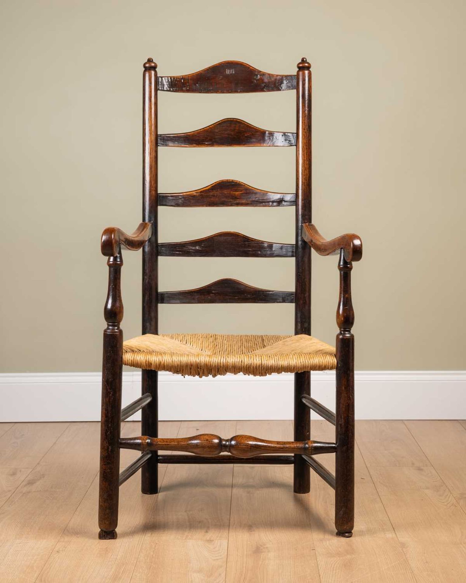 An ash framed ladder back chair with rush seat, stamped 'WA' to the seat back, on turned supports,