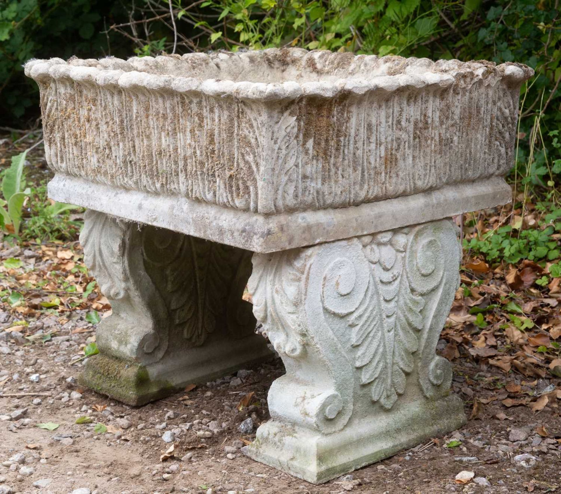 A cast reconstituted stone square planter, with acanthus leaf decoration, on scrolling supports,