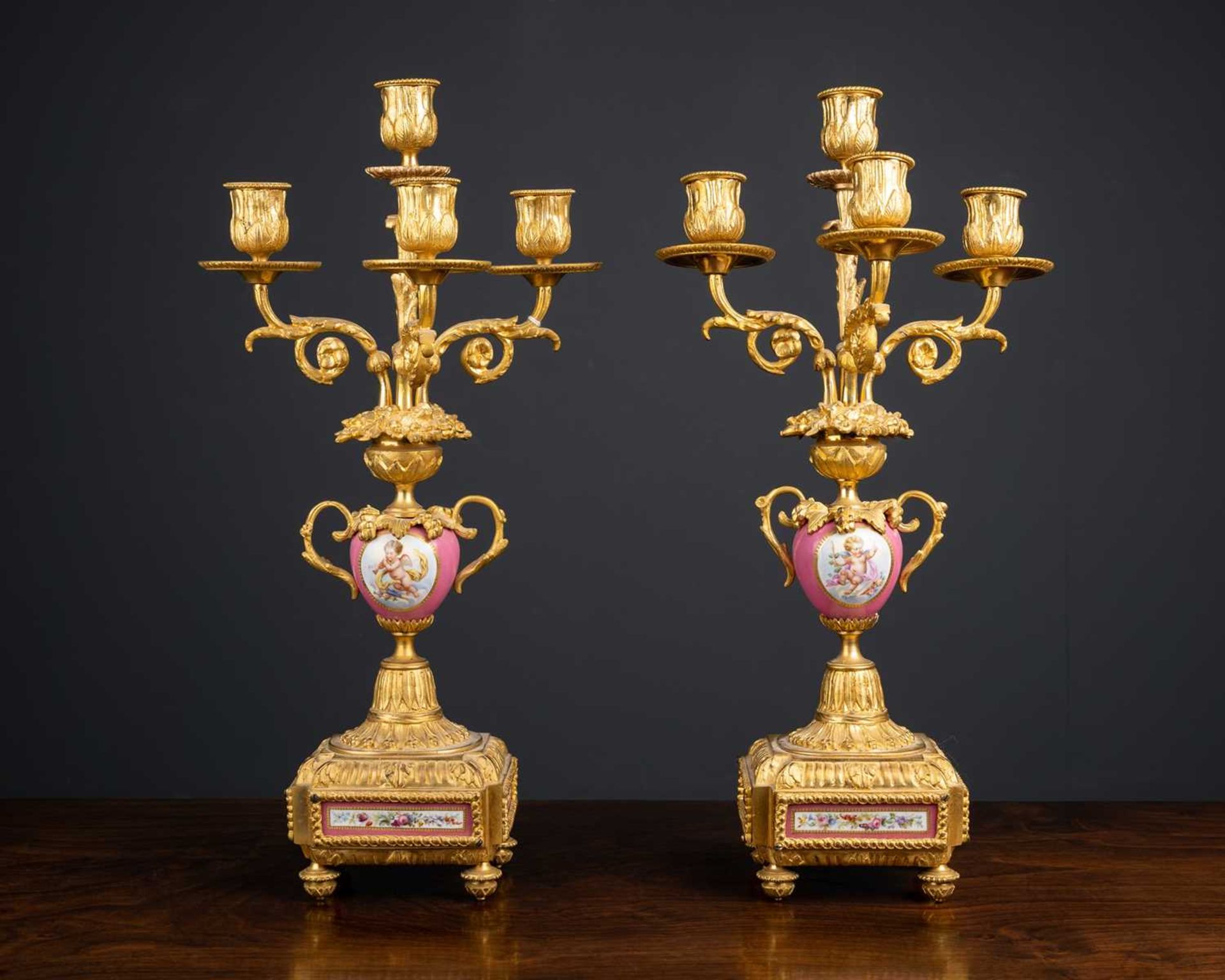 A pair of ormolu and porcelain candelabra, the pink porcelain bodies with cherub panel, 43cm high (