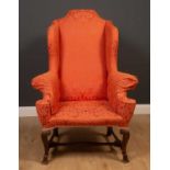 A Georgian mahogany high wingback armchair on scrolling supports united by an H-frame stretcher,