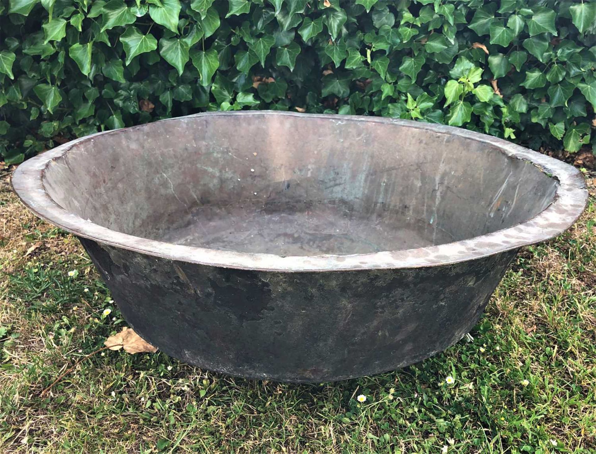 A large continental shallow copper bowl, with rivetted patches, 76cm diameter, 25.5cm highWith