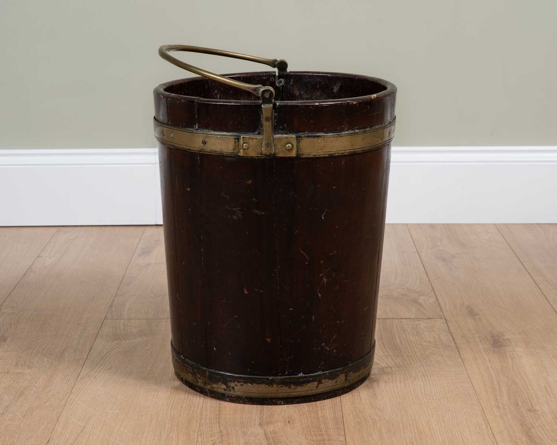 A George III brass bound mahogany peat bucket with hinged looping handle and later zinc liner,