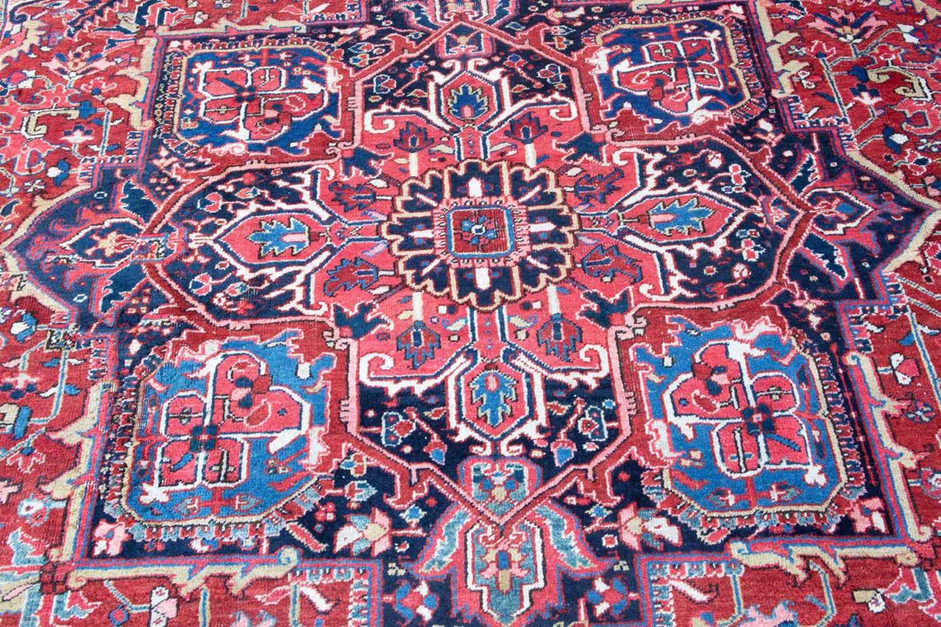 A Middle Eastern Heriz red and blue ground carpet the border with polychrome floral heads around a - Image 5 of 6