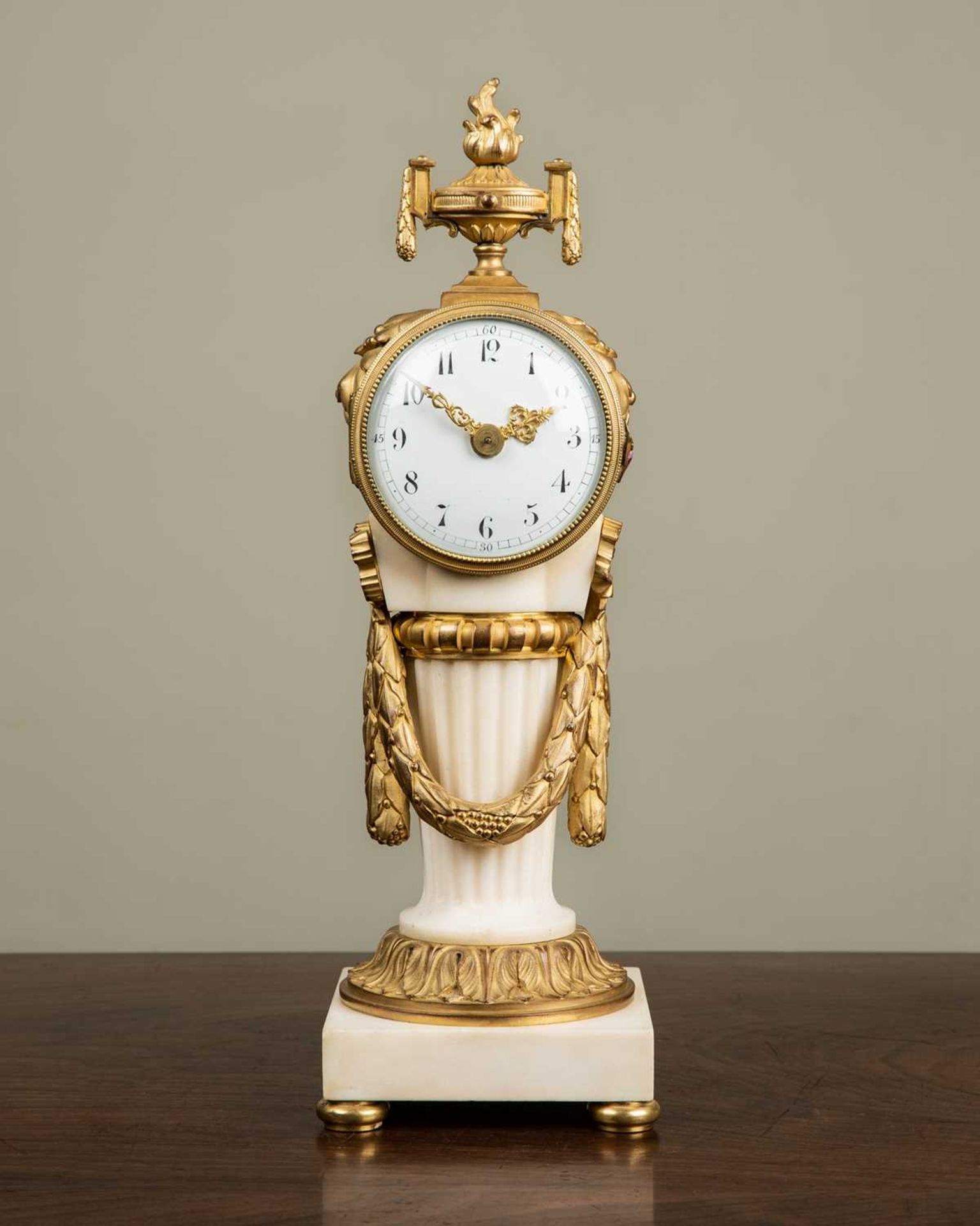 An early 20th century French ormolu and marble timepiece in the Classical style, with flaming vase