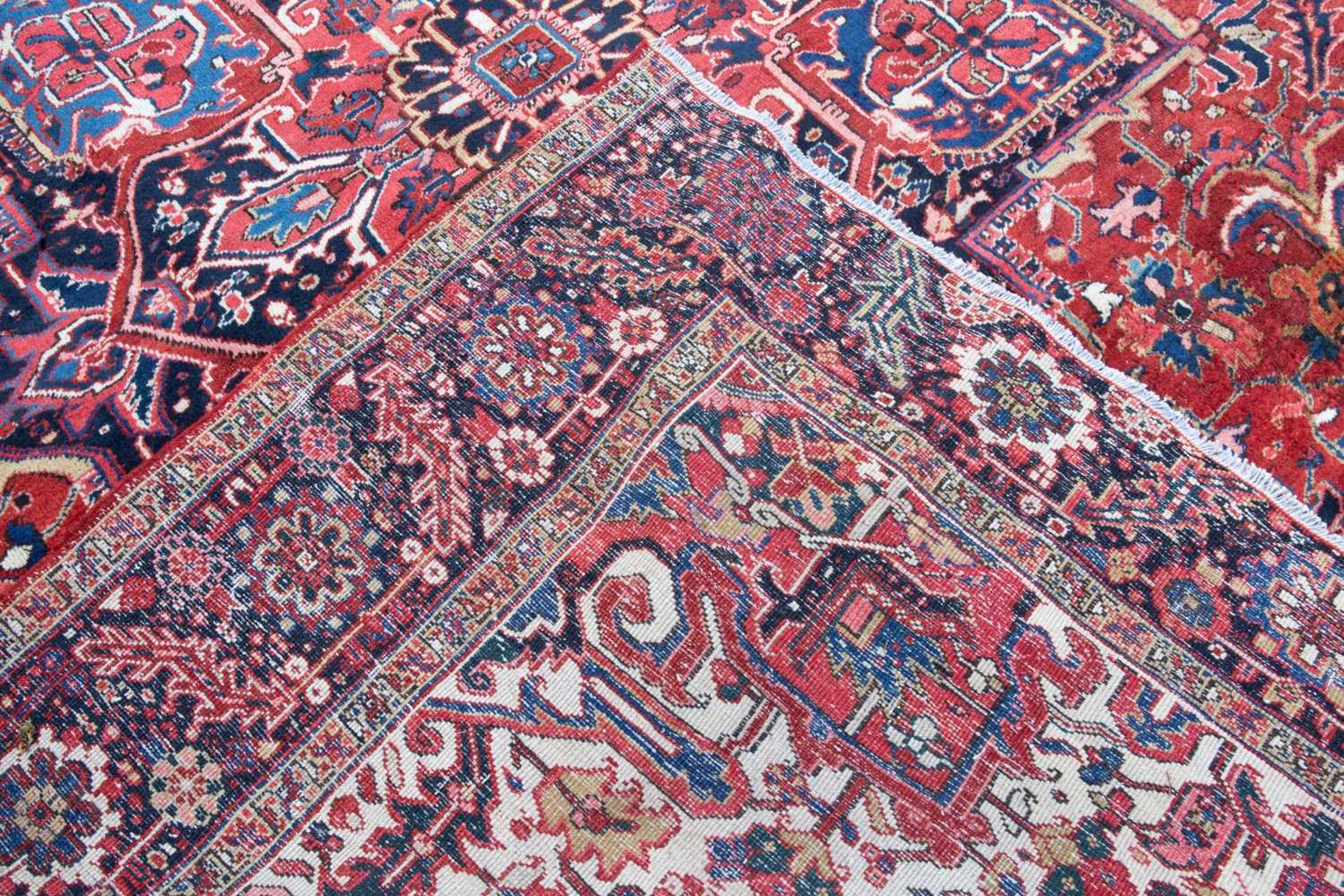 A Middle Eastern Heriz red and blue ground carpet the border with polychrome floral heads around a - Image 6 of 6