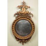A Regency gilt convex wall mirror with decorative spouting dolphin crest, the original mirror