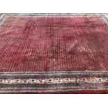 An oriental carpet, the central red ground decorated with a dense pattern of geometric shapes within