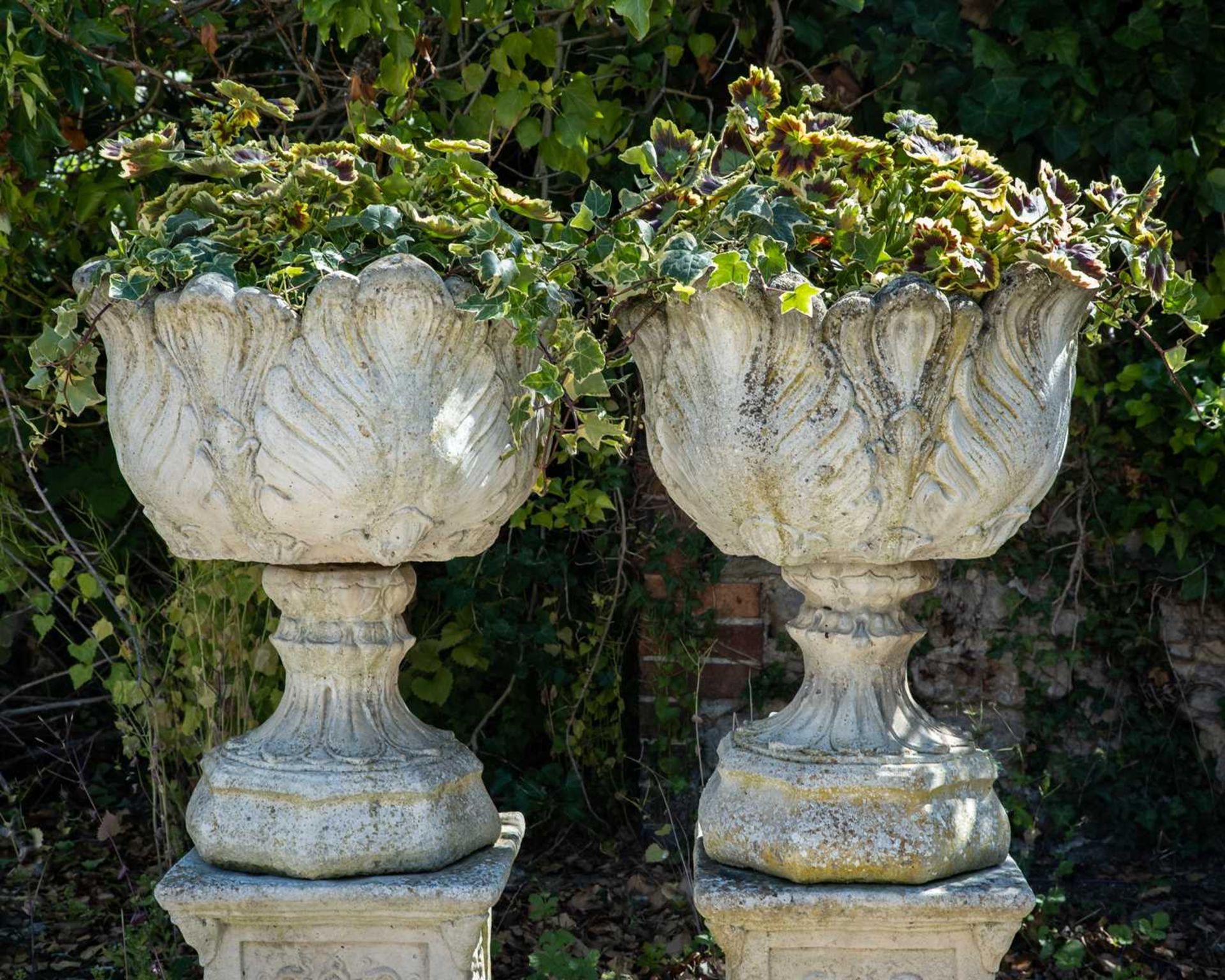 A pair of cast reconstituted stone garden urns decorated with acanthus leaves on octagonal bases and - Image 3 of 4