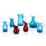 Collection of Whitefriars glass jugs of various designs, kingfisher blue, ruby red, tallest measures