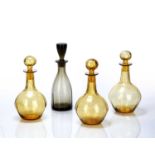 Attributed to Harry Powell for Whitefriars Four glass decanters, three in amber, one in pewter