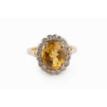 A citrine and diamond cluster ring, the oval mixed-cut citrine in claw setting, bordered by round