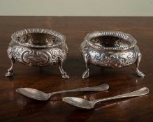 A pair of Victorian bun salts, each raised on three cloven feet and with floral and scrolling