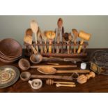 A collection of approximately twenty carved wooden spoons in rack, together with five wooden
