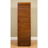 An early 20th century oak tambour fronted tall narrow cabinet, the fitted interior with various