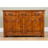 A Georgian-style oak dresser base with three drawers over pair of cupboard doors on square feet,