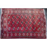A red ground rug with all over geometric shapes within a brown and black banded border, 130cm x