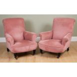 A pair of Howard style armchairs with pink upholstery on turned supports and castors, 84cm wide x