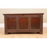 An oak coffer with three panelled front and carved stylised decoration, on low feet, 118cm wide x