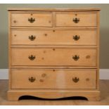 A pine chest of two short over three long drawers, with brass handles and escutcheons, on low