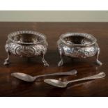 A pair of Victorian bun salts, each raised on three cloven feet and with floral and scrolling